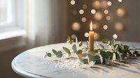 Elegant white candle with eucalyptus garland on round table creating cozy atmosphere with warm bokeh lights background for home decor and celebration.