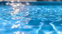 Sparkling blue water surface with sunlight reflections creating bokeh effect and gentle ripples, abstract aquatic background for spa and wellness designs.