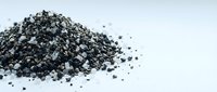 Pile of black activated charcoal granules scattered on white background for detox, filtration and purification applications in health and industry.