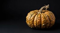 Golden textured pumpkin with ridged segments isolated on dark background, suitable for autumn designs, fall decorations, and seasonal marketing materials.