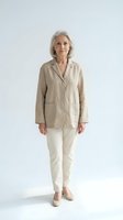 Senior woman with gray hair wearing beige linen blazer and cream pants, standing against white background. Suitable for mature fashion, business casual, and lifestyle marketing.