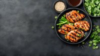 Grilled teriyaki chicken wings with green onions and sesame seeds served on black plate against dark background. Asian cuisine with copy space for menu.