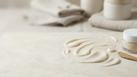Creamy cosmetic product swirled on beige surface with skincare jars and applicator, showcasing luxury beauty and skincare product presentation for cosmetics marketing.