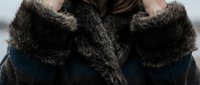 Woman wearing luxurious dark fur collar coat in winter fashion portrait showcasing elegant outerwear and sophisticated style for cold weather clothing.