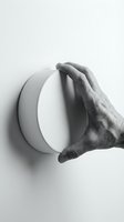Hand protecting white circular object on wall in monochrome minimalist composition for design and conceptual projects.