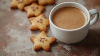 Hot chocolate in white ceramic mug with homemade star-shaped butter cookies on rustic brown surface. Cozy winter drink and festive holiday treats.