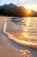 Golden sunset over mountain lake creates sparkling reflections on gentle waves washing ashore, capturing serene moment as sun dips behind peaks.