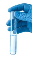 Gloved hand in blue latex holding a clear test tube with liquid sample on white background for science and medical concepts.