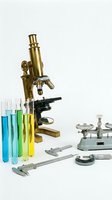 Vintage brass microscope with colorful test tubes and precision measuring tools on white background for scientific research and laboratory work.