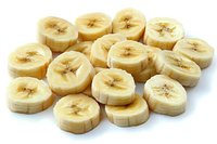 Fresh sliced banana pieces arranged on white background, showing natural yellow fruit texture and cross-sections with seeds, isolated for food design.