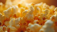 Fresh popcorn kernels in extreme macro shot with warm golden lighting and shallow depth of field, creating appetizing texture for food marketing.