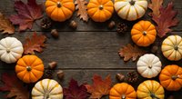 Autumn pumpkins and fall leaves arranged in circle on rustic wooden background with acorns and pine cones for seasonal harvest decoration and thanksgiving design.