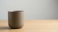 Minimalist ceramic mug with neutral beige tone on wooden surface, isolated on white background, ready for product mockup, branding, and design applications.