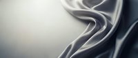 Smooth flowing silver and charcoal silk fabric with elegant waves and folds, creating luxurious abstract patterns suitable for fashion, textile, and design backgrounds.