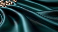 Luxurious dark teal silk fabric with soft folds and waves creates elegant background texture, complemented by scattered gold pearls in corner for luxury design.