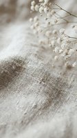 Delicate white baby's breath flowers on natural linen fabric texture creating soft romantic atmosphere for wedding invitations and feminine design projects.