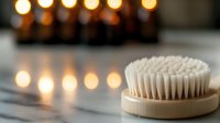 Wooden dry brush for body massage and skincare routine with warm candles creating relaxing spa atmosphere for wellness and self-care treatments.