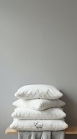 Stacked white linen pillows on wooden surface with folded towels, neutral minimalist home decor and bedding display for interior design projects.