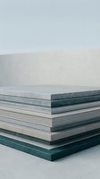 Stack of ceramic or stone tile samples in neutral gray and teal tones arranged on a concrete surface for interior design and renovation concepts.