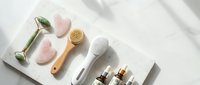 Skincare beauty tools and cosmetic products arranged on white marble surface with natural lighting for spa wellness routine and self-care rituals.