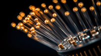 Glowing orange LED lights on electronic circuit board create dramatic technological pattern against dark background, macro photography closeup.