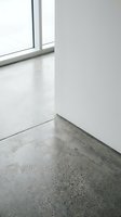 Minimalist interior corner with polished concrete floor and white wall near window for modern architectural design projects.