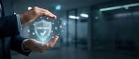 Businessman hands protecting glowing compliance shield icon with checkmark in modern office environment for corporate security and regulatory standards.