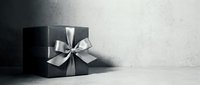 Elegant black gift box with silver satin ribbon bow on gray concrete background, luxury present for holidays, birthdays, or special occasions.