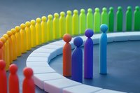 Colorful wooden figures arranged in curved formation, rainbow gradient from red to green with blue figures in foreground, representing diversity and community.