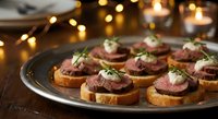 Elegant beef crostini appetizers topped with cream sauce and herbs on a silver platter, warm bokeh lights in background, festive holiday party setting.