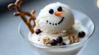 Playful snowman dessert made from vanilla ice cream scoop with chocolate chips and carrot nose, decorated with cookies and berries in glass bowl.