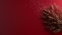 Delicate golden branch with sparkles against deep red background creates magical festive mood for holiday designs and winter season decorations.
