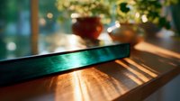 Sunlight streaming through window creates dramatic shadows on wooden surface with blurred plant decor in background, moody morning atmosphere.