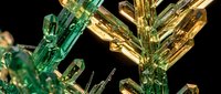 Stunning green and yellow crystal formations with prismatic light reflections creating geometric patterns against dark background for luxury design projects.