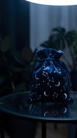 Mystical celestial drawstring pouch with moon and star constellation pattern sits on glass table in moody blue lighting for spiritual practices.