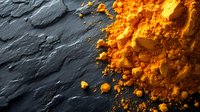 Vibrant orange turmeric powder scattered on dark slate stone background, creating dramatic contrast and texture for culinary and wellness concepts.