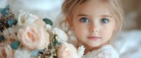 Young girl with bright blue eyes and blonde hair in lace dress poses near delicate peach roses and white flowers, soft dreamy panoramic portrait.