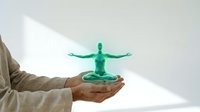 Hands holding glowing green holographic human figure in meditation pose representing wellness technology, digital health innovation and mindfulness concepts.