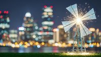 Miniature windmill with bright light burst against blurred city skyline at night, renewable energy concept for environmental sustainability projects.