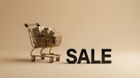 Shopping cart filled with boxes next to bold SALE text on beige background, retail discount and seasonal promotion concept.