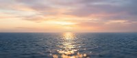 Serene ocean sunset with golden sunlight reflecting on calm water surface, peaceful seascape for relaxation and travel themes.
