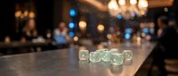 Translucent dice with glowing numbers on dark surface in upscale venue with blurred bokeh lights and guests, suitable for gaming, entertainment, and event marketing.