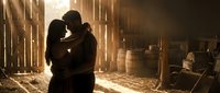 Romantic couple silhouette embracing in rustic barn with golden sunlight streaming through wooden slats creating warm intimate atmosphere for love stories.
