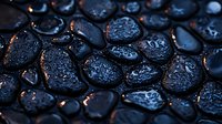 Wet black stones with water drops in dark moody lighting create zen spa atmosphere, macro photography shows texture details and reflective surfaces.