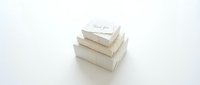 Stack of elegant white gift boxes with thank you card on top, arranged in pyramid shape on white background for wedding or celebration.
