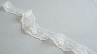 Delicate ivory lace trim with floral embroidery and scalloped edges on white background, isolated for sewing, crafts, and textile design projects.