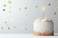 White birthday cupcake decorated with gold sprinkles and single burning candle on light background with festive bokeh lights and copy space for text.
