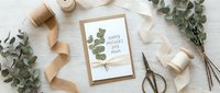 Elegant flat lay composition with eucalyptus branches, kraft paper card, golden ribbon and vintage scissors on white wooden background for crafting.