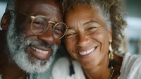 Happy mature African American couple smiling together, elderly black man with glasses and gray beard embracing senior woman with curly hair, love and joy.