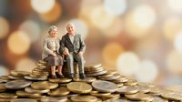 Senior Caucasian couple figurines sitting on golden coins stack with warm bokeh background representing retirement savings and financial security planning.